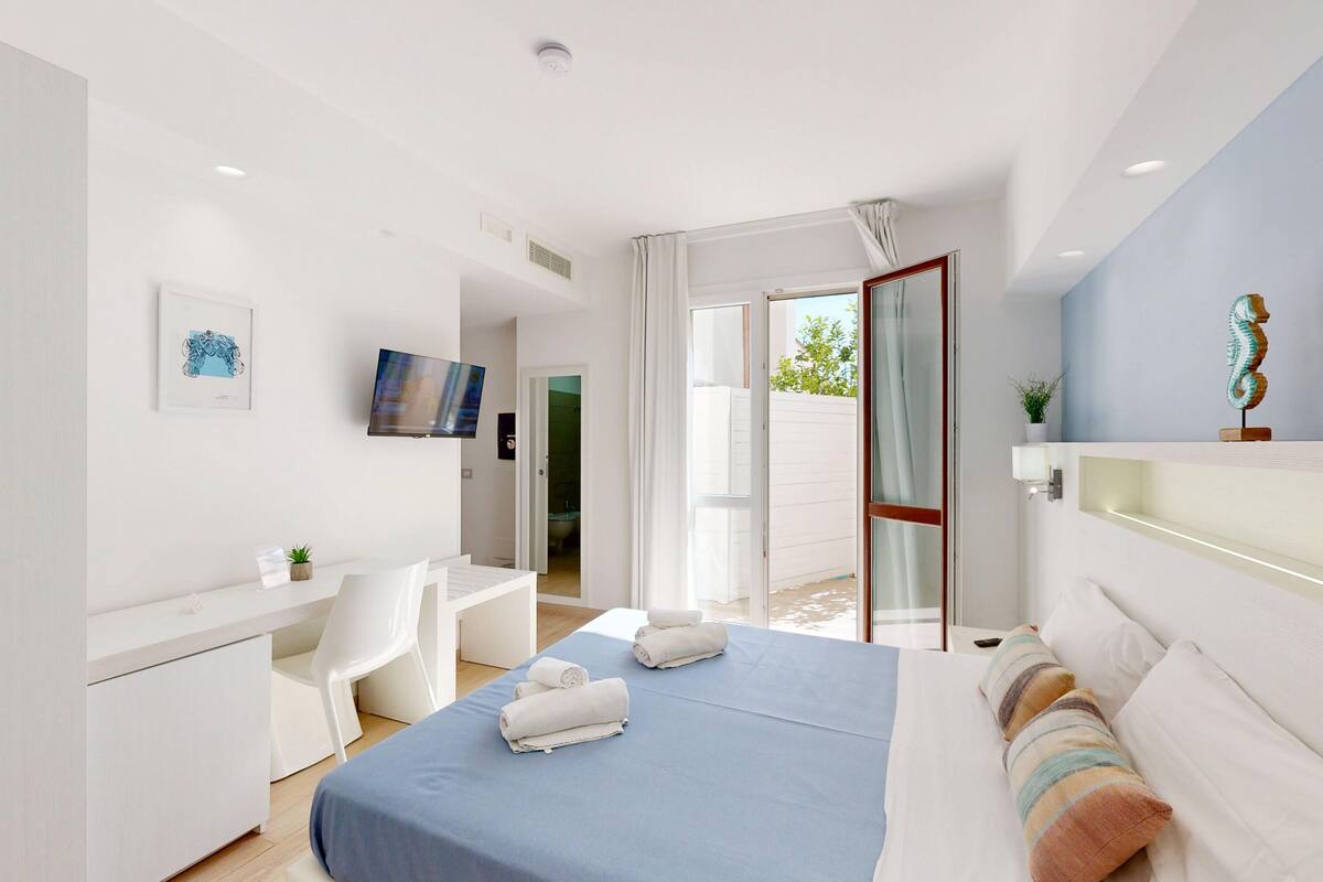 Een moderne hotelkamer met een bed, bureau, stoel en een televisie.