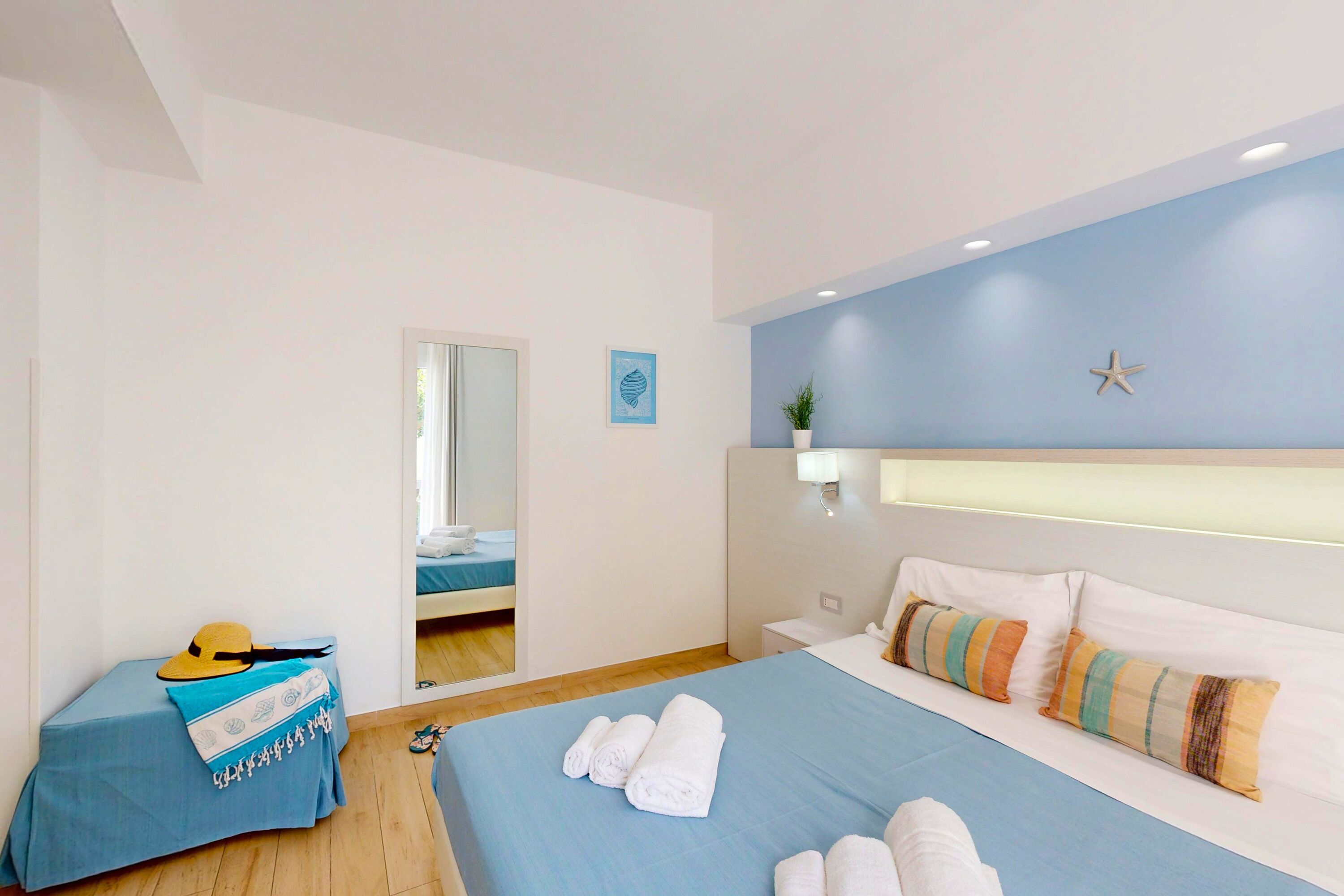 Ein Hotelzimmer mit Bett, Nachttisch, Spiegel, Fenster und Tür.