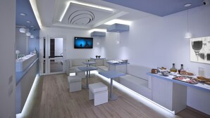 A modern kitchen with a central island, built-in appliances, and a flat-screen TV. - Hotel Perla Gaia (San Vito Lo Capo)