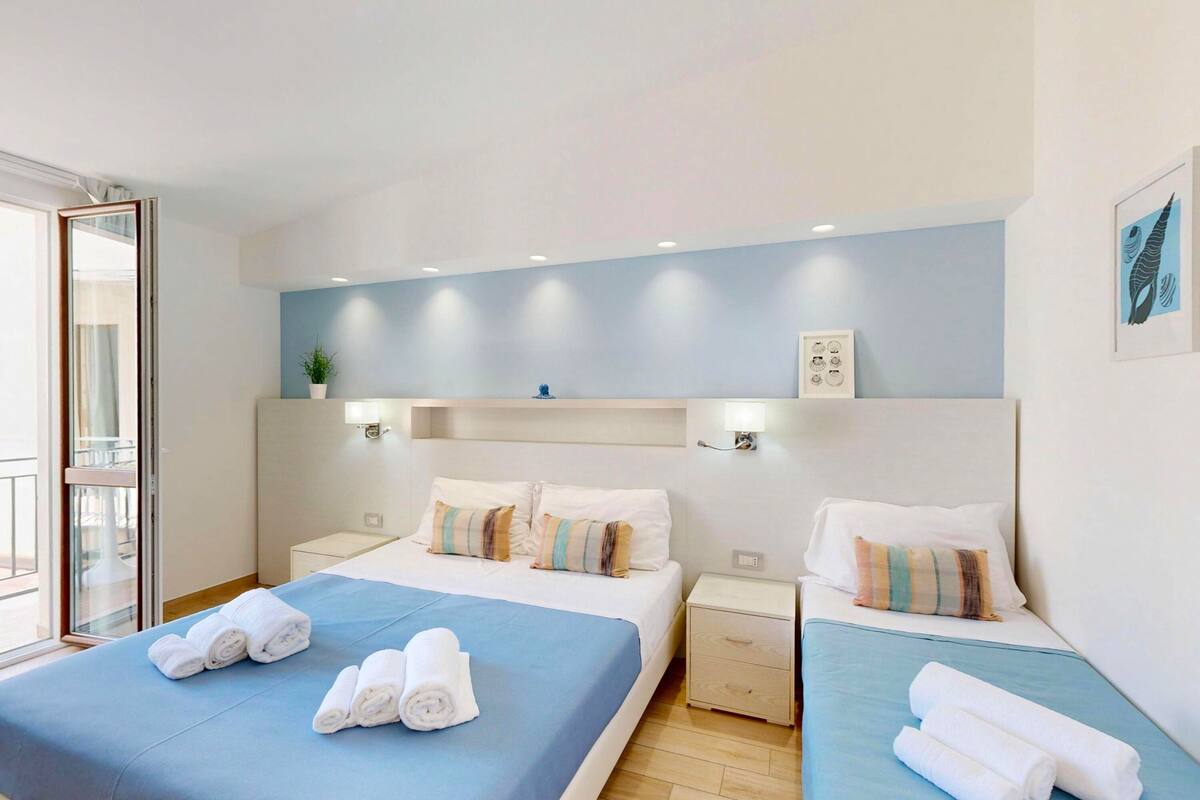 Een hotelkamer met een bed, twee nachtkastjes, een wandlamp en een raam met uitzicht.