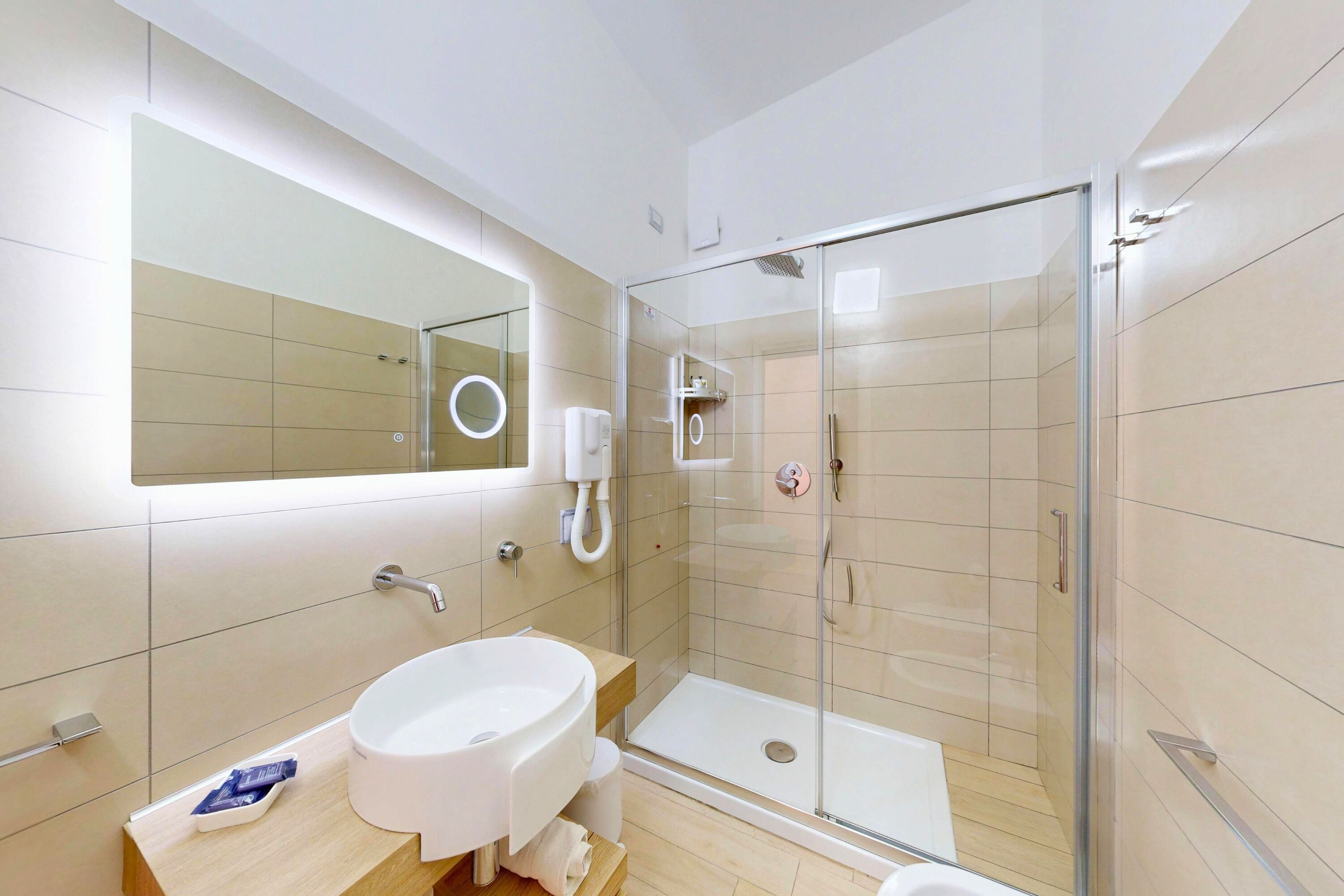 Une salle de bain moderne avec une douche à parois de verre, un lavabo blanc et un grand miroir.