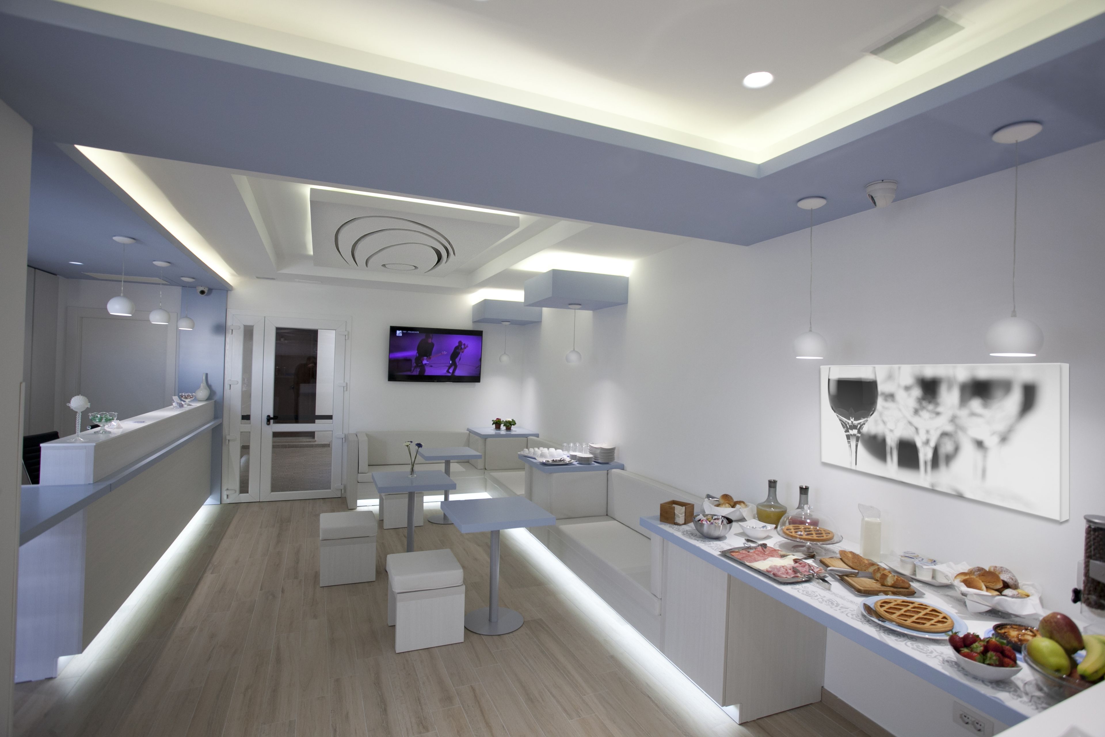 A modern kitchen with a long counter, seating area, and a TV.
