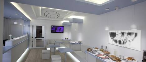 A modern kitchen with a long counter, seating area, and a TV.