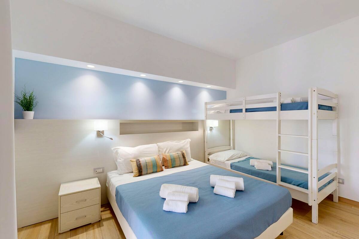 Een slaapkamer met stapelbedden, een nachtkastje en een wandlamp.