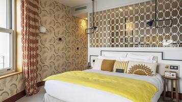 Hotelkamer met een groot bed, decoratieve wand, raam met gordijnen en nachtkastje met een radio.