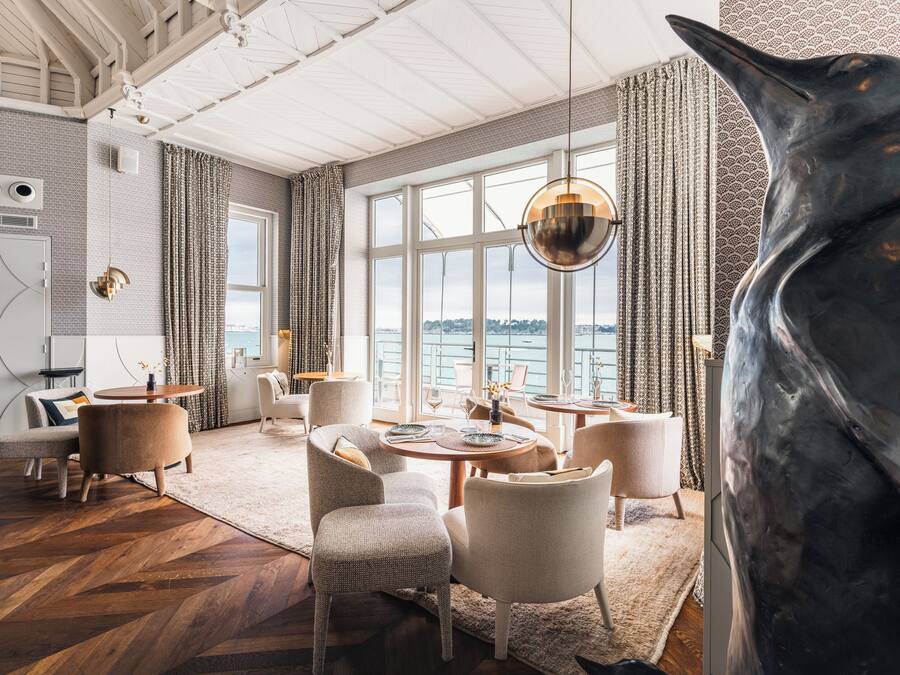 Un interior moderno con un gran ventanal, una zona de comedor y una escultura original.