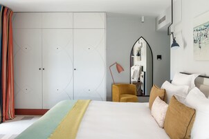 Una habitación de hotel con una cama grande, un armario, un espejo y un escritorio con lámpara.