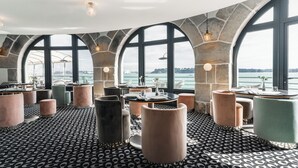 A modern restaurant with a nautical theme, featuring stone arches, large windows with a view of the sea, and a patterned floor. - Castelbrac Hôtel & Spa (Dinard)