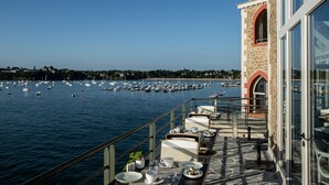 A terrace with tables and chairs overlooking a marina with boats. - Castelbrac Hôtel & Spa (Dinard)
