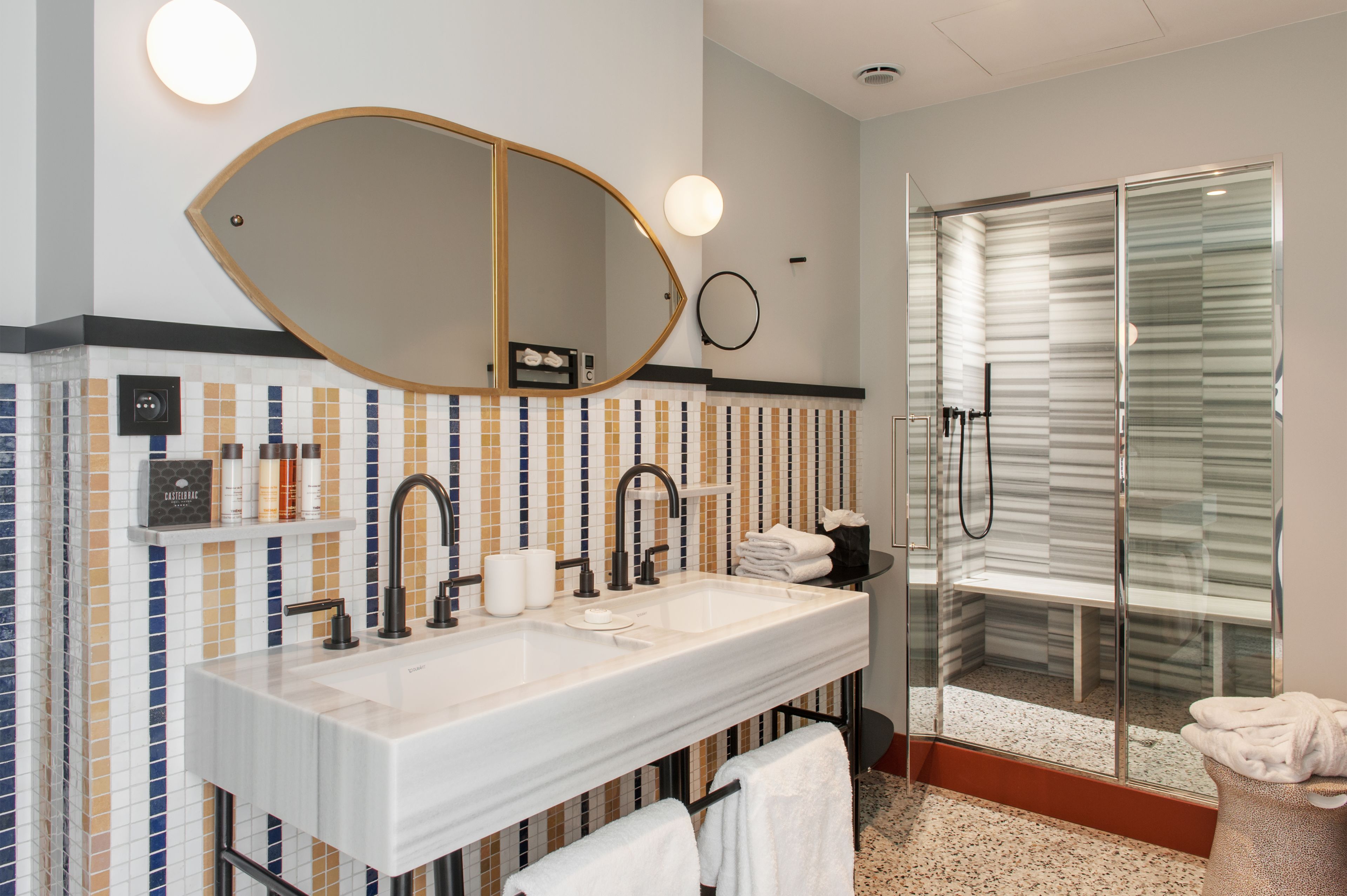 A modern bathroom with a dual sink vanity, a large mirror, and a glass-enclosed shower.
