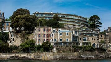 A waterfront hotel with a stone facade, multiple balconies, and a view of the water.