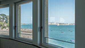 A bathroom with a bathtub, large windows, and a view of the sea. - Castelbrac Hôtel & Spa (Dinard)