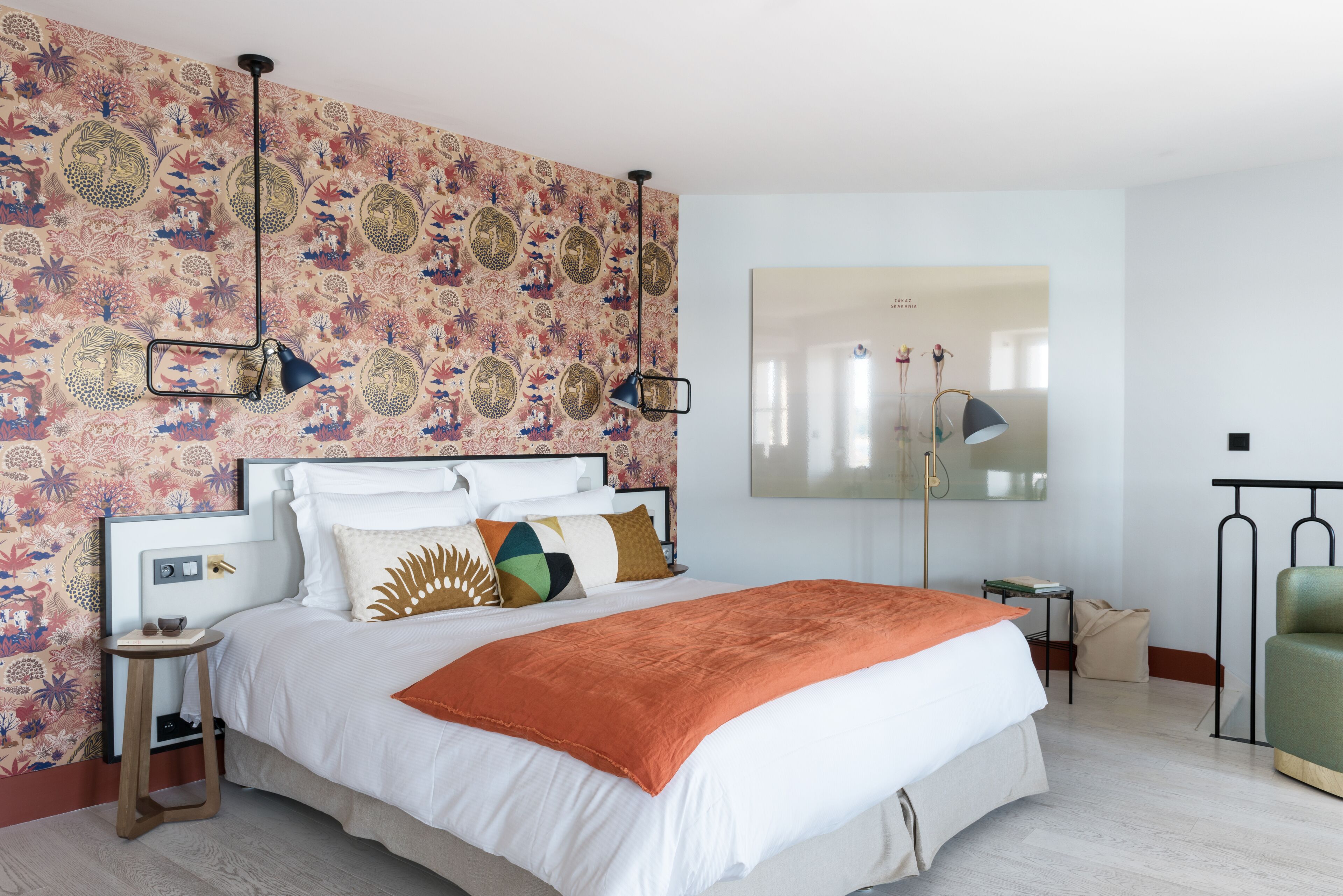Une chambre moderne avec un grand lit, un papier peint à motifs et un miroir au mur.