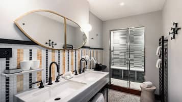 Un baño moderno con lavamanos doble, un espejo grande y cabina de ducha de vidrio.
