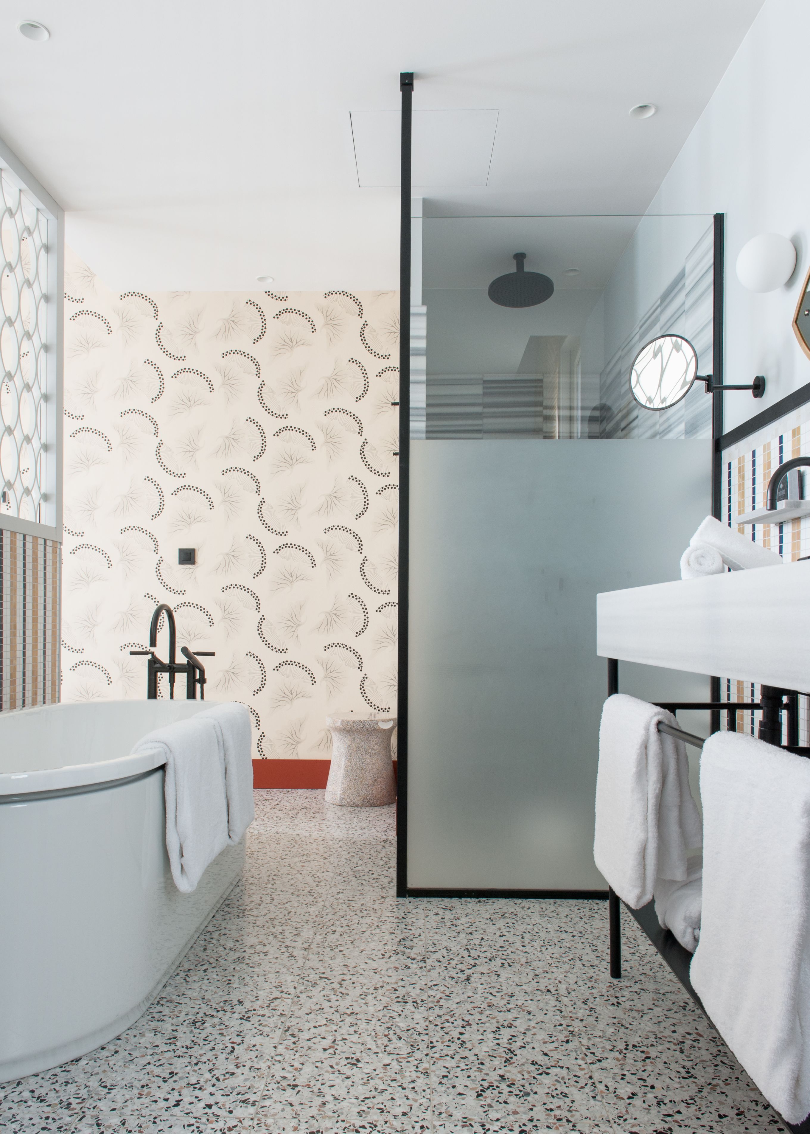 A modern bathroom with a freestanding bathtub, a glass shower enclosure, and a vanity with a mirror.
