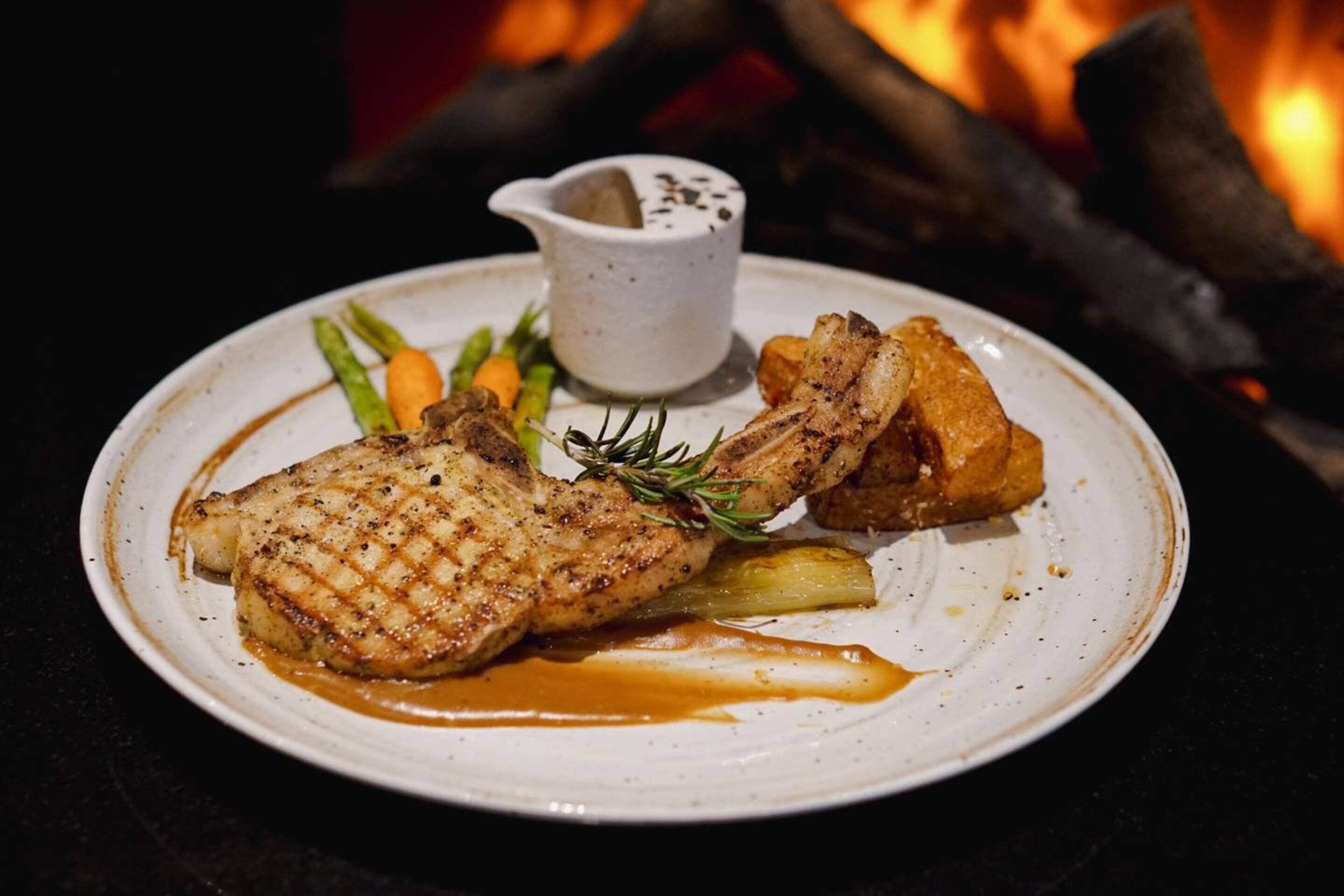Une assiette de viande grillée accompagnée de légumes et un petit bol de sauce.