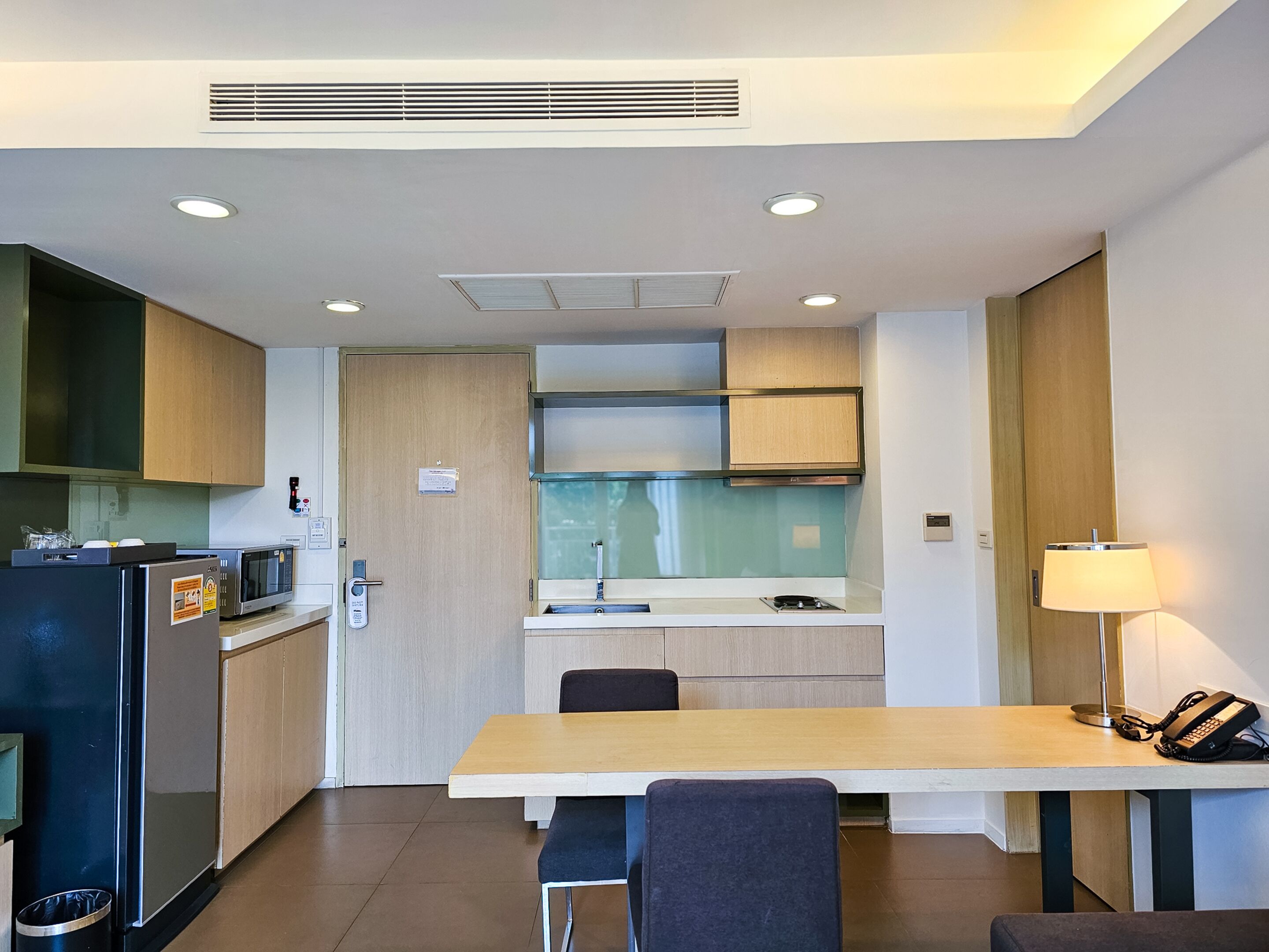 A compact kitchen with a microwave, refrigerator, and a small window.
