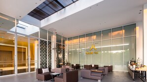 A modern hotel lobby with glass walls, comfortable seating, and a visible reception desk. - The Idle Hotel and Residence (Khlong Luang)
