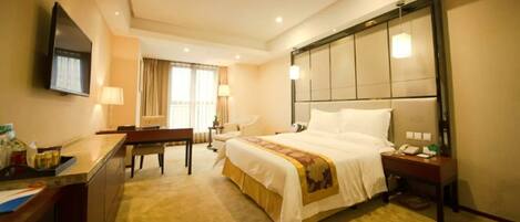 A hotel room with a bed, bedside table, desk, chair, and a TV mounted on the wall.