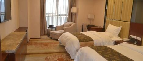 A hotel room with two beds, a desk, a chair, a TV, and a window with curtains.