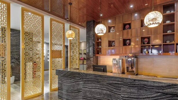 A reception area with a wooden reception desk, decorative screens, and a marble-like counter. - Antai Century Hotel (Chengdu)