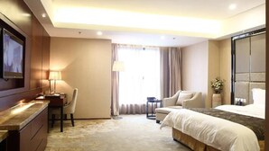 A hotel room with a large bed, a desk with a chair, a TV, and a large mirror. - Antai Century Hotel (Chengdu)