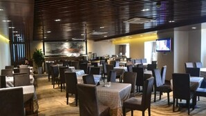 A hotel dining area with multiple tables and chairs, a large painting on the wall, and a television screen. - Antai Century Hotel (Chengdu)