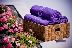 A wicker basket with rolled purple towels and pink and white flowers beside it. - Sesmarias Turismo Rural & SPA (Cuba)