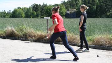 To personer spiller bold på en grussti, med et skilt der viser 'BOULDROME' i baggrunden.