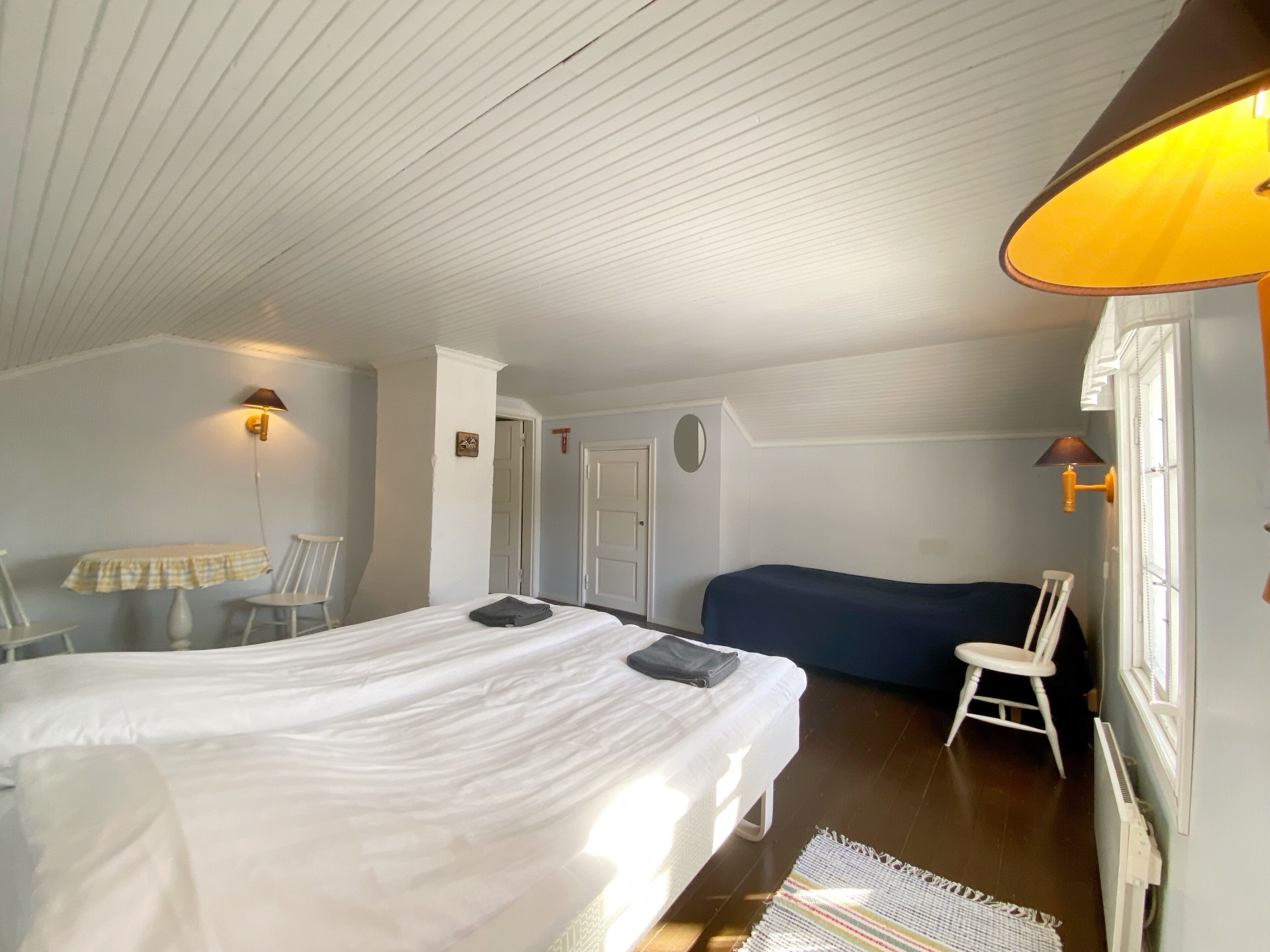 Een slaapkamer met een bed, een bureau, een stoel, een bank en een lamp.