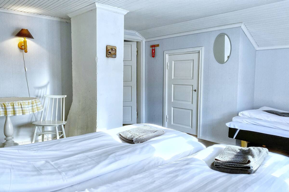 Ein Hotelzimmer mit einem Bett, einem Sessel, einer Lampe, einem Spiegel und einer Tür.