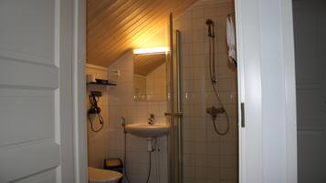A small bathroom with a toilet, sink, and shower.