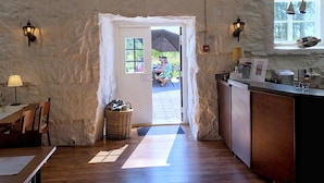 Un interior rústico con suelo de madera, paredes de piedra, una barra con un menú y una puerta que da al exterior.
