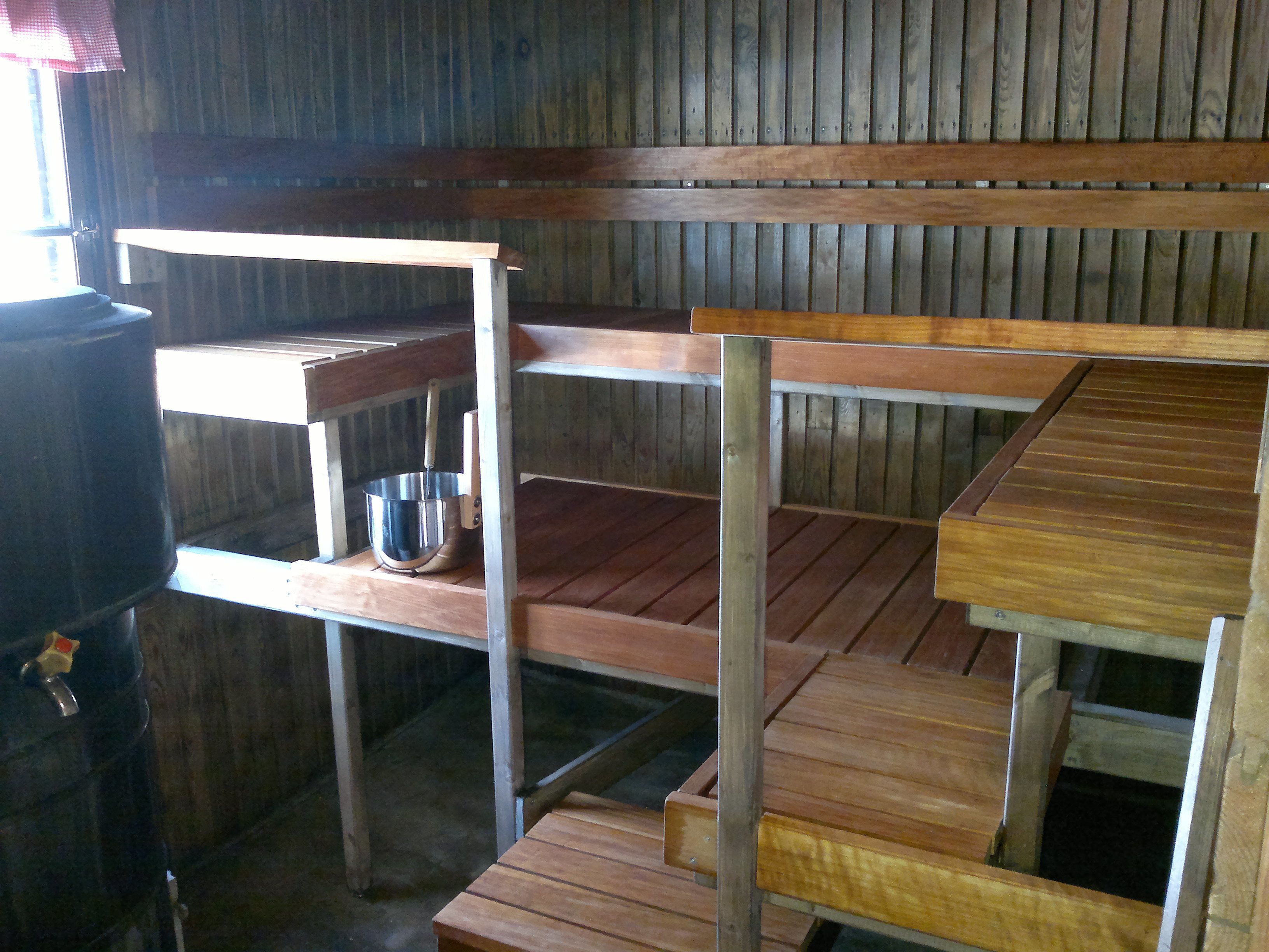 A rustic wooden interior with a metal shelf unit, a metal bucket, and a wooden table.