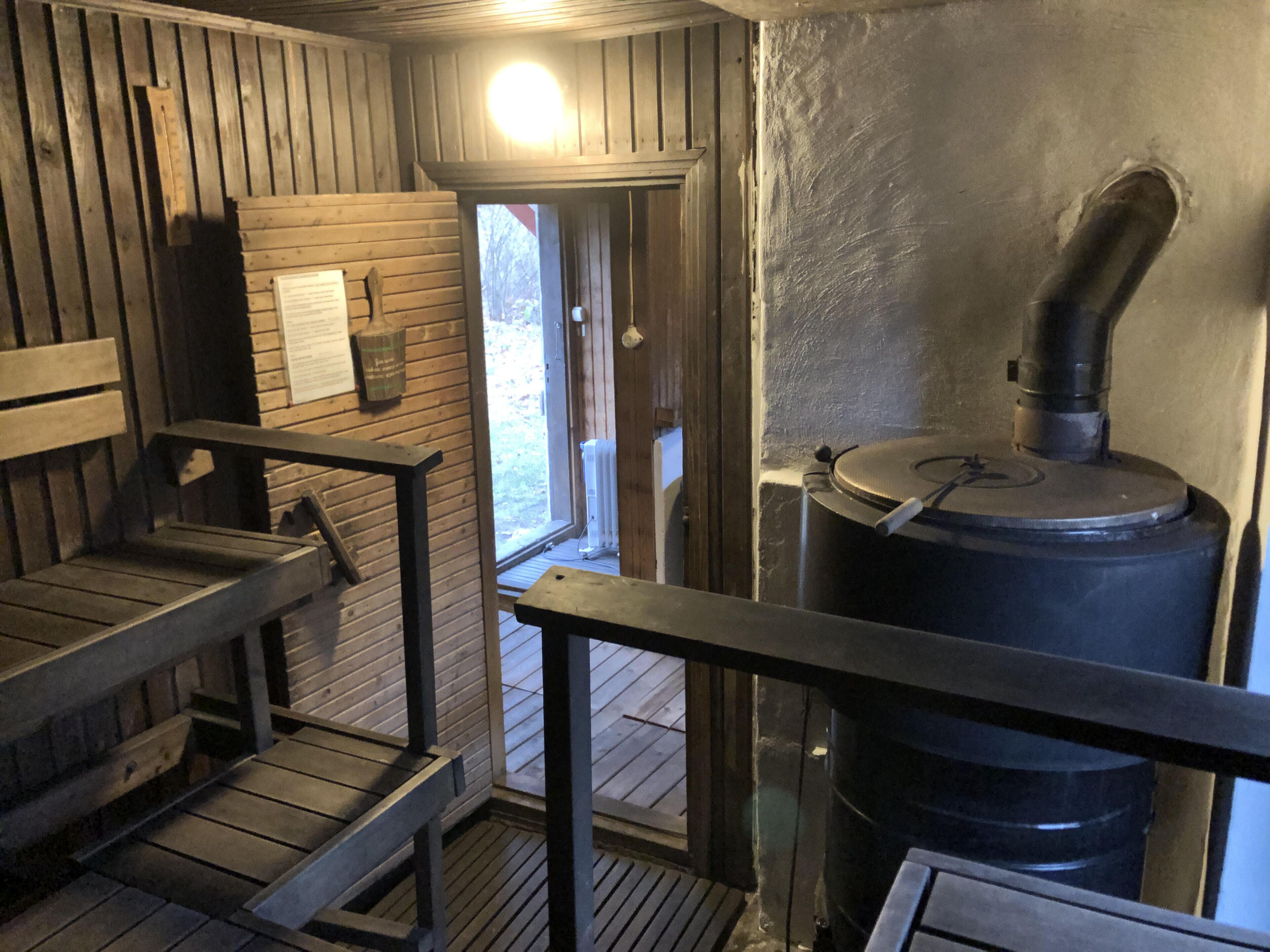 Een sauna met houten banken en een grote sauna-kachel.