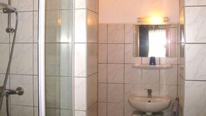 Un baño con cabina de ducha de vidrio, lavabo y espejo con luz superior.