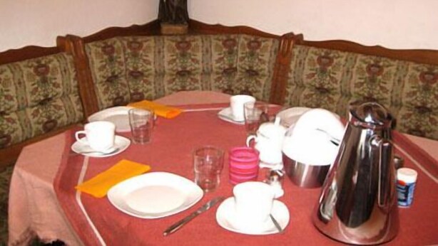 Mesa para cuatro personas dispuesta, con una estatua en lo alto, rodeada de sillas tapizadas con estampado floral.