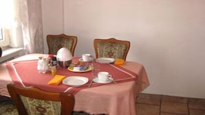Una mesa de comedor dispuesta con platos, tazas y una jarra, rodeada de sillas con tapicería floral.
