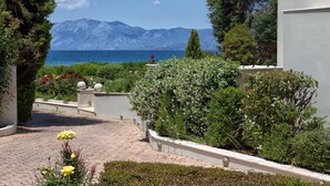 Un sentier de jardin qui mène à un point de vue sur la mer, avec des montagnes en arrière-plan.