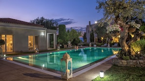 Une piscine offrant une vue dégagée sur les bâtiments environnants, notamment un immeuble avec un toit en tuiles et un arbre en fleurs.