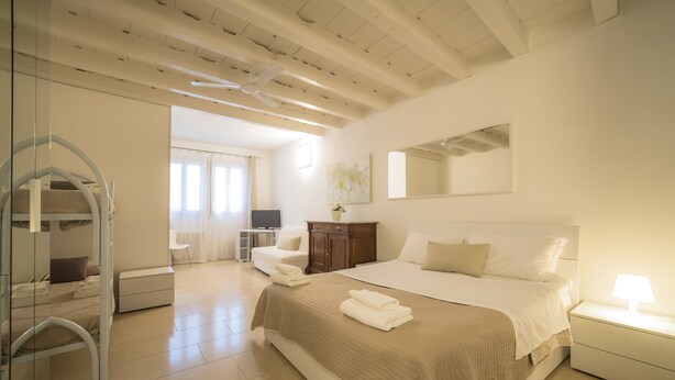 A spacious bedroom with a large bed, a wardrobe, a desk, and a chair.