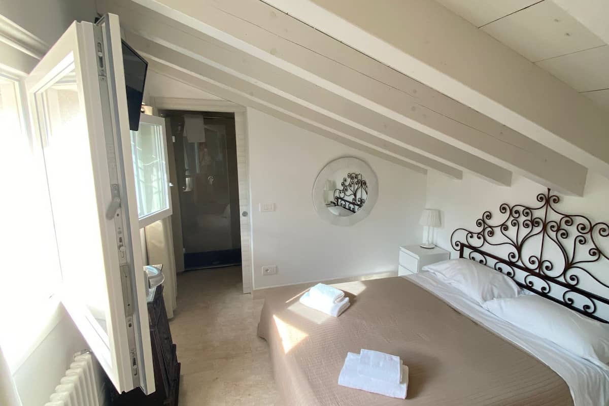 Ein Schlafzimmer mit Bett, Heizkörper, Fenster und Tür.
