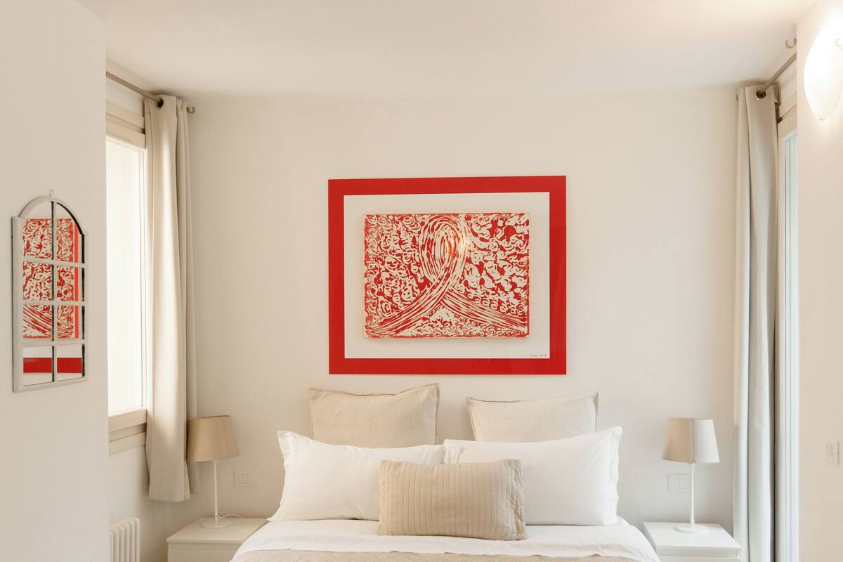 Ein ordentlich eingerichtetes Schlafzimmer mit einem großen Bett, zwei Nachttischen und einem Wandbild.