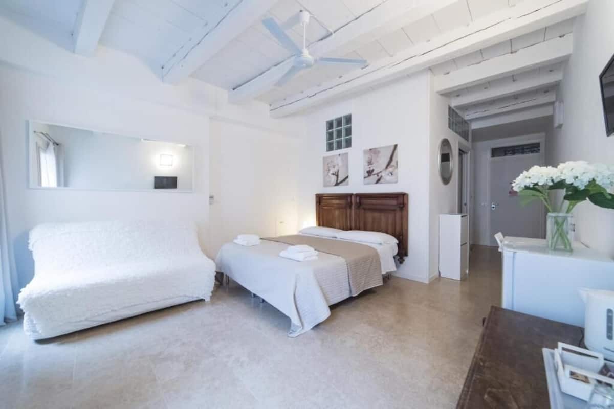 Ein Schlafzimmer mit zwei Betten, einem Deckenventilator, einem Spiegel und Bildern an der Wand.