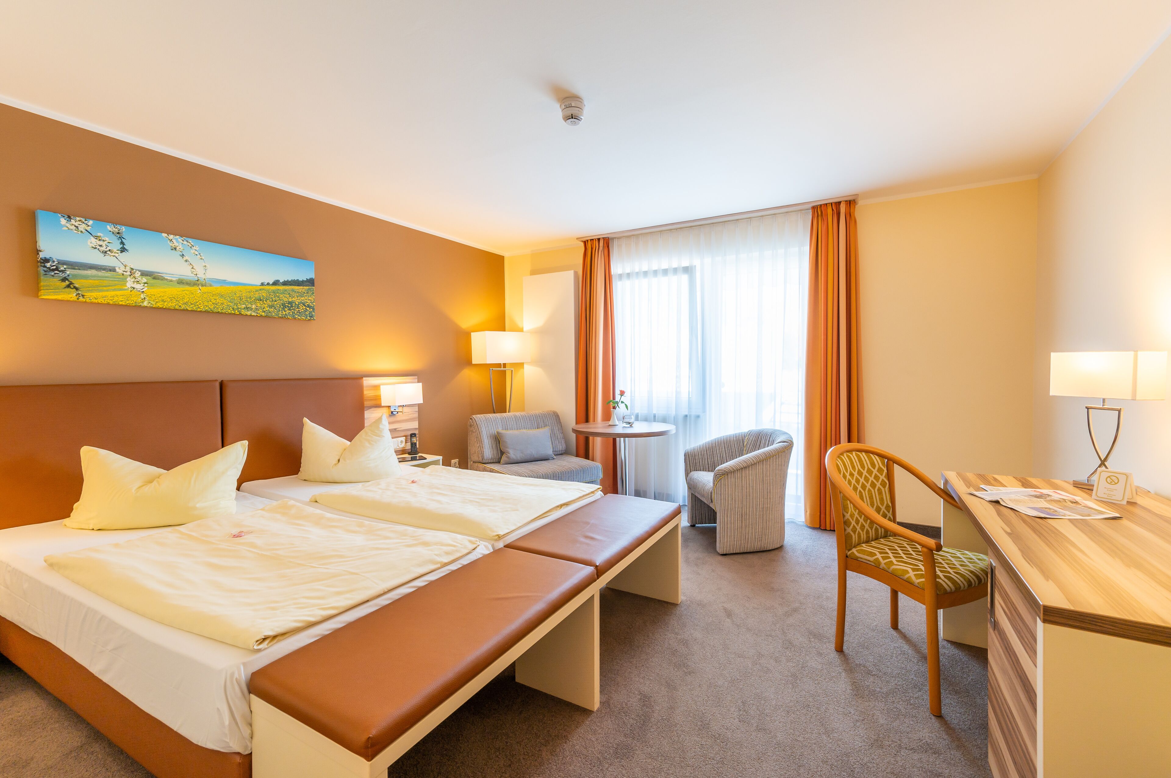 Une chambre d’hôtel avec deux lits, un bureau, une chaise et un tableau au mur.