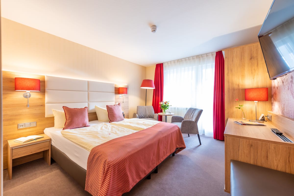 Une chambre d’hôtel avec un grand lit, des tables de chevet, un bureau, une chaise et un téléviseur.