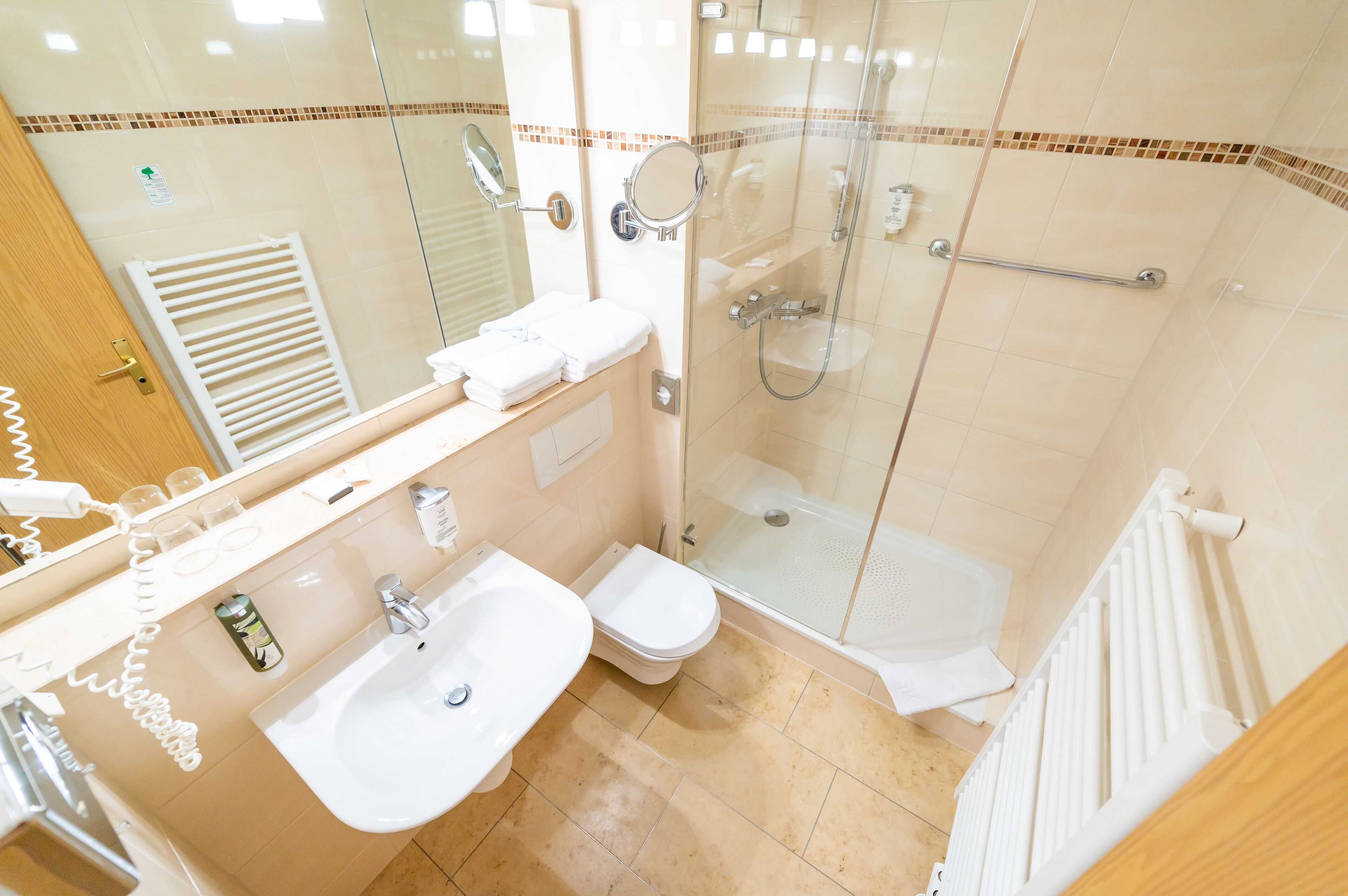 Een moderne badkamer met een douchecabine van glas, een wastafel en een toilet.