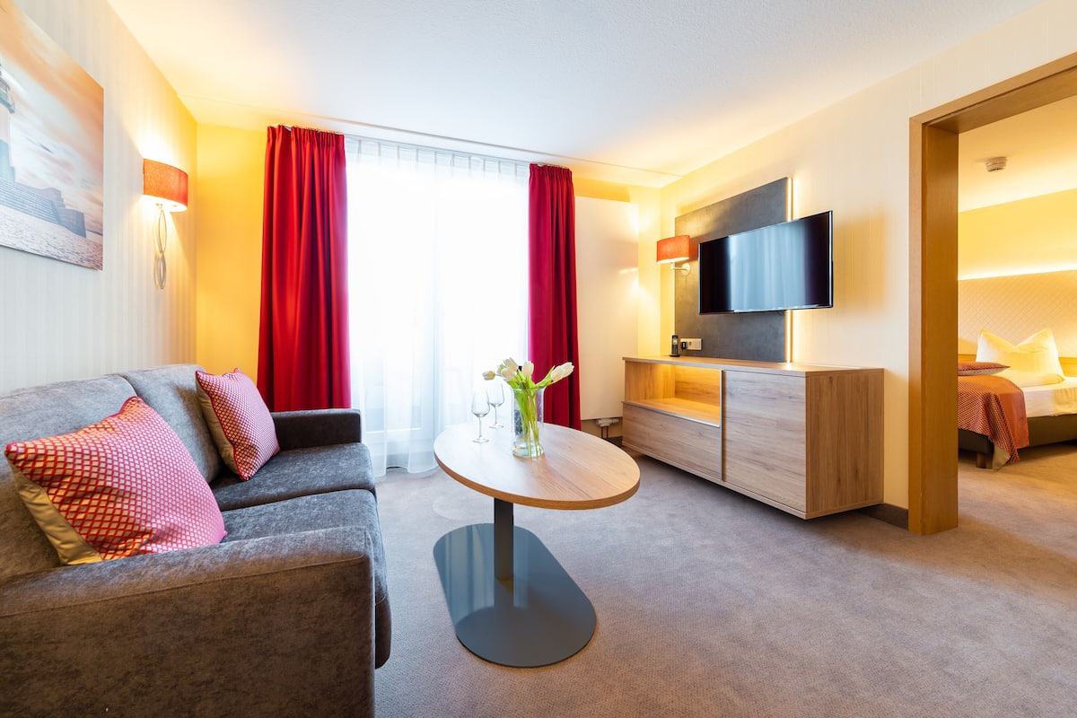 Une chambre d’hôtel moderne avec un canapé, une petite table ronde, un téléviseur et un lit.