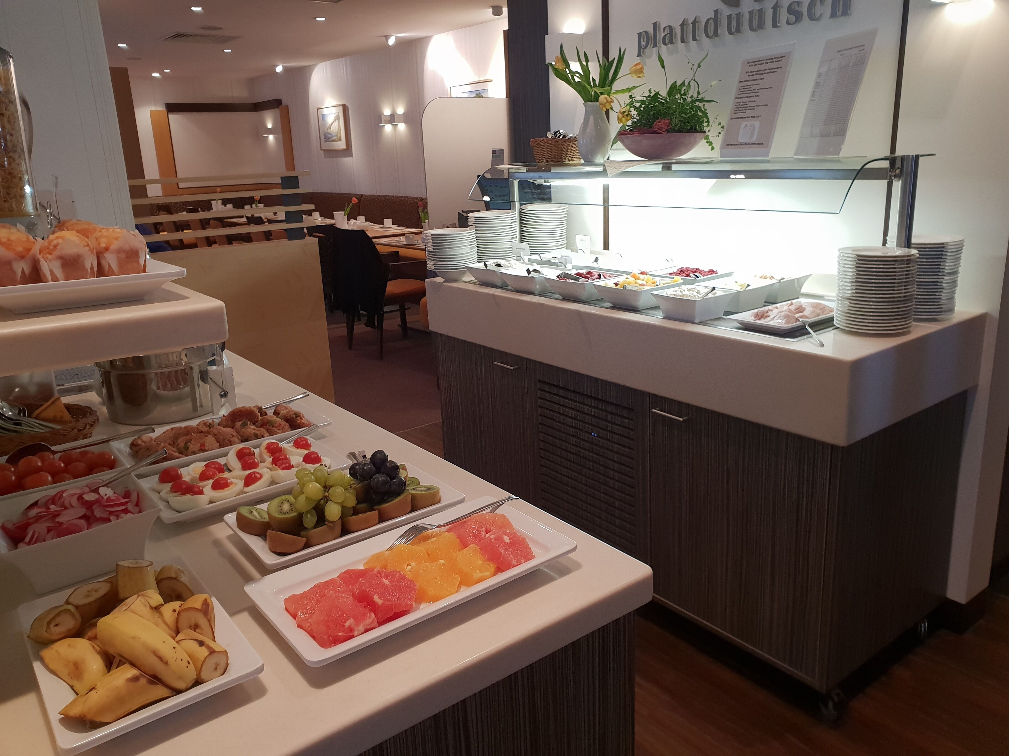 A buffet area with various food options including fruits, meats, and pastries.