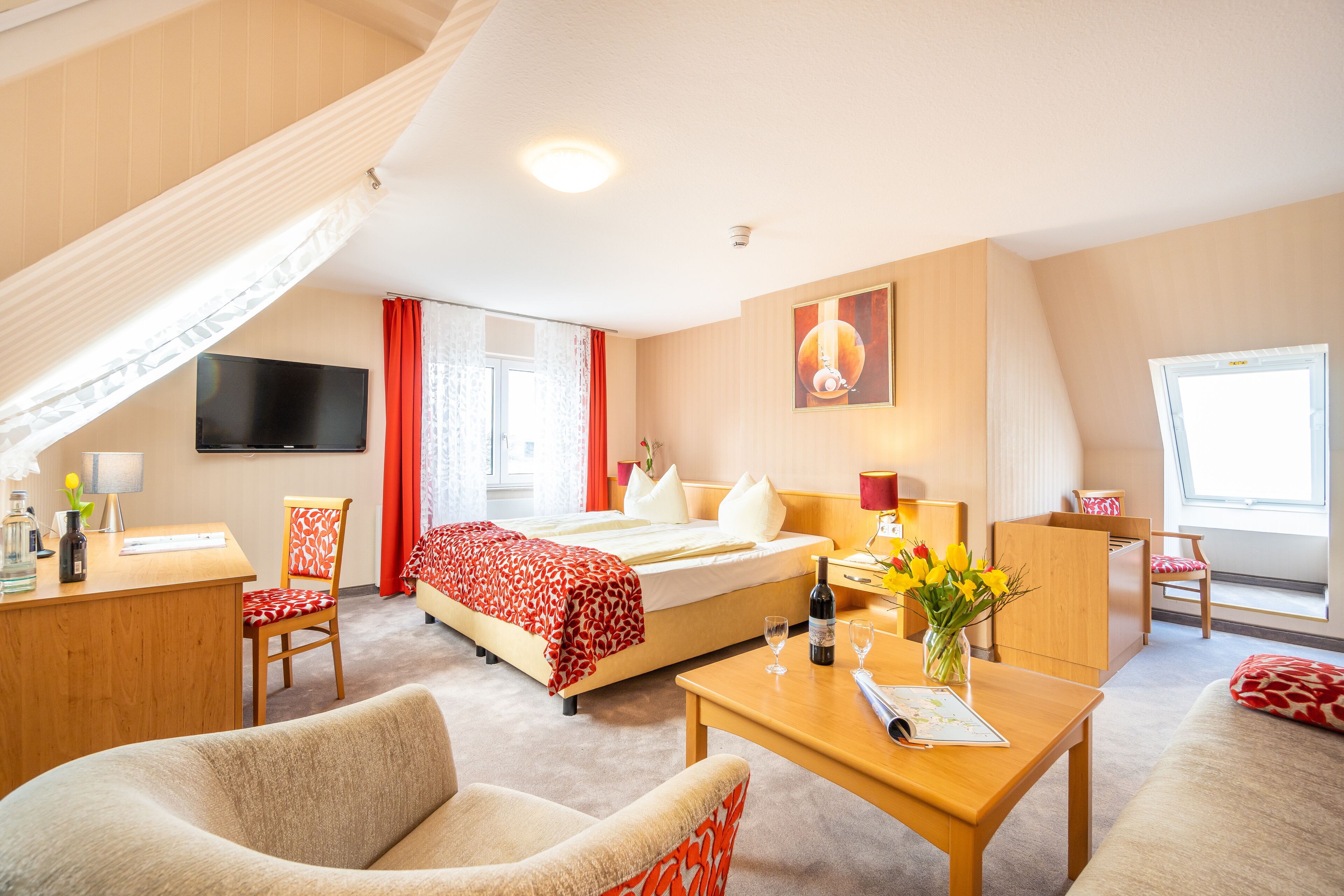 Ein Hotelzimmer mit Bett, Schreibtisch, Stuhl und Fernseher.